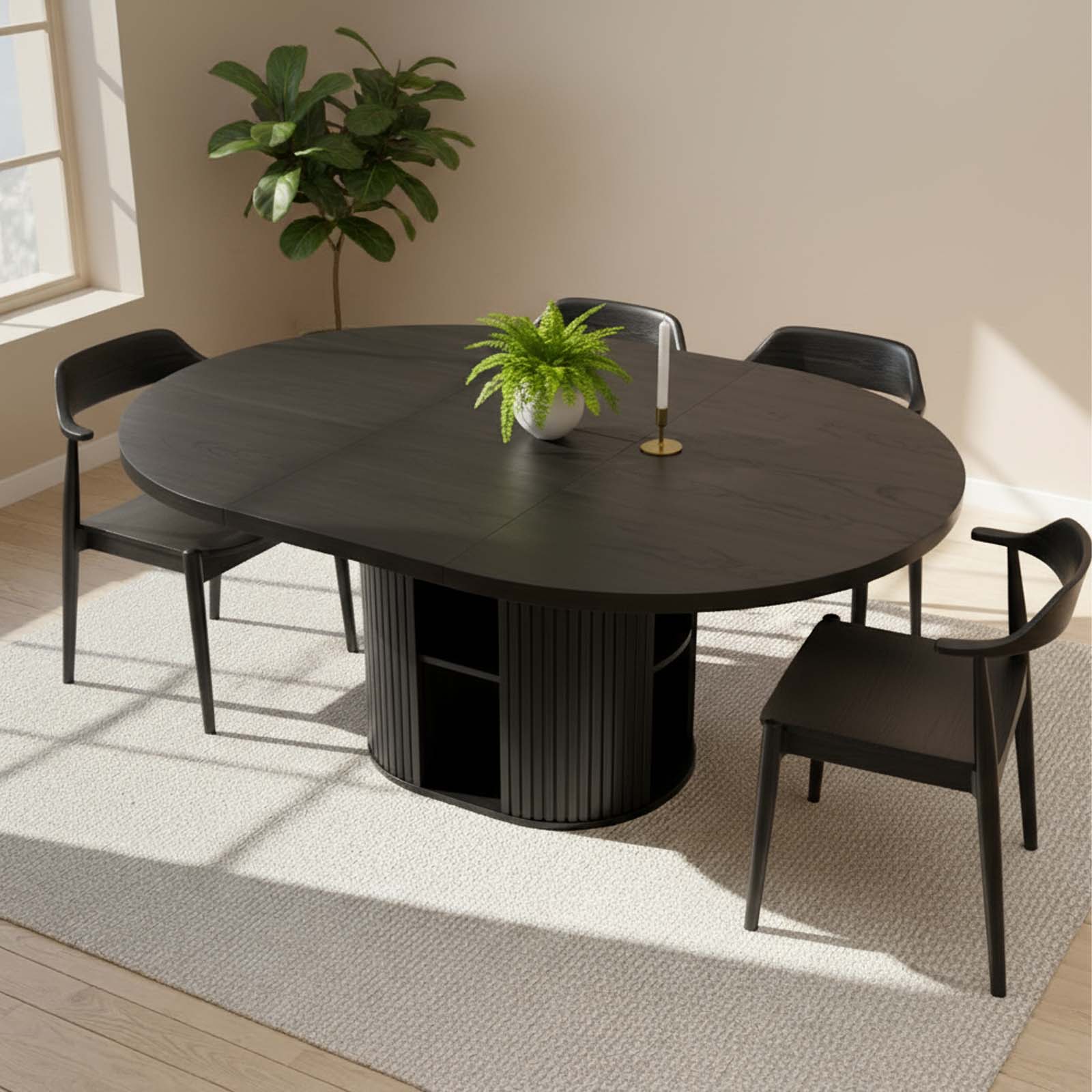 Black dining table with four chairs in a well-lit room with a plant and decor items.