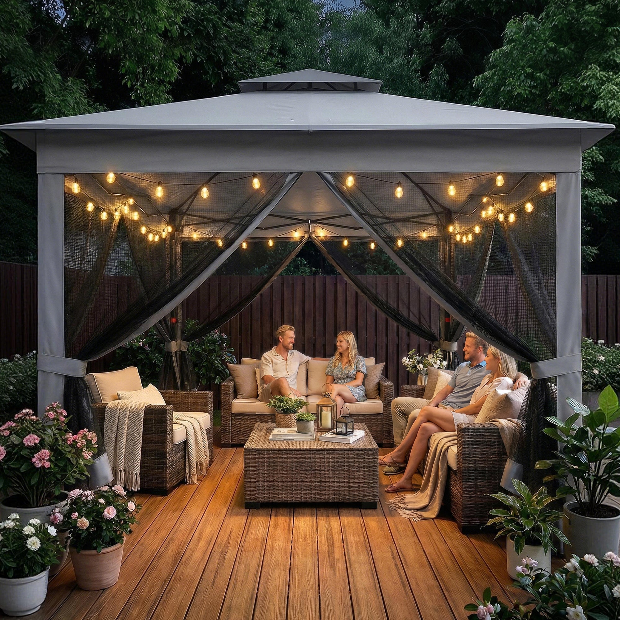 People sitting under a lit outdoor gazebo on a wooden deck with string lights and plants.