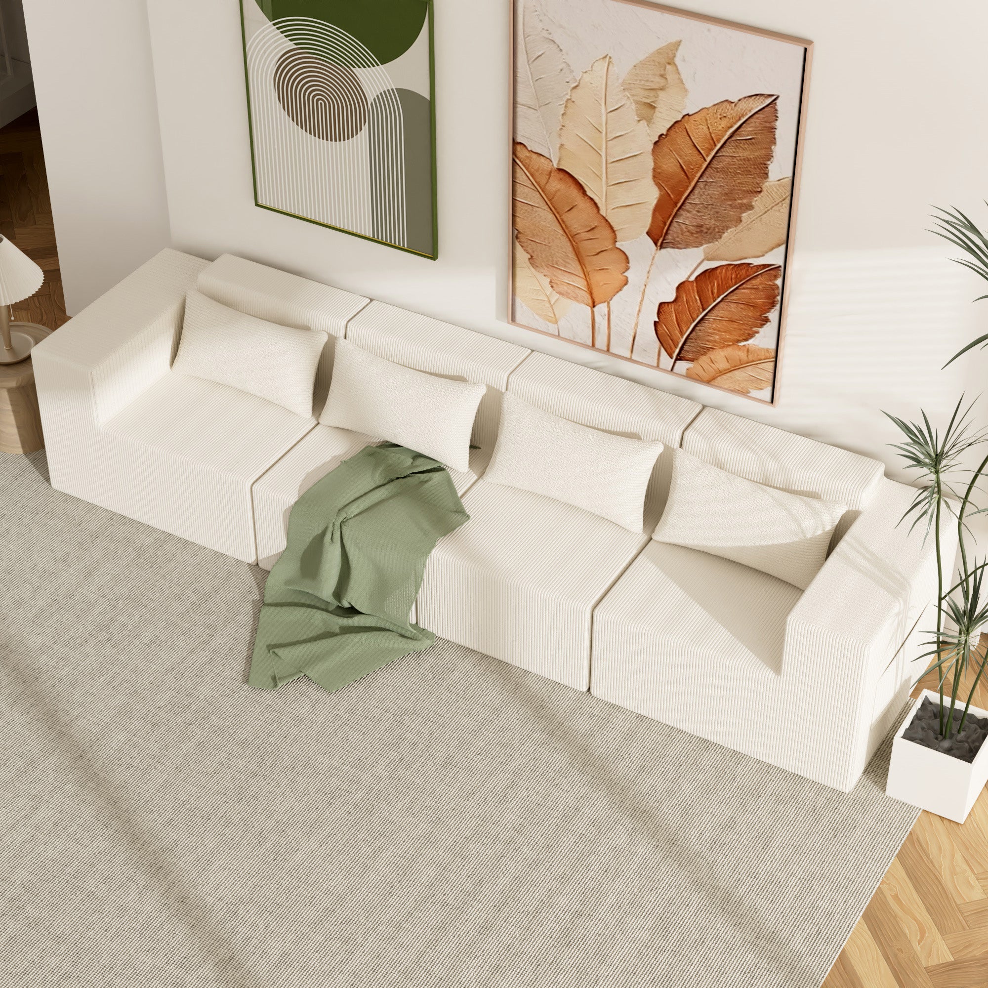 White sectional sofa with a green blanket in a living room setting.