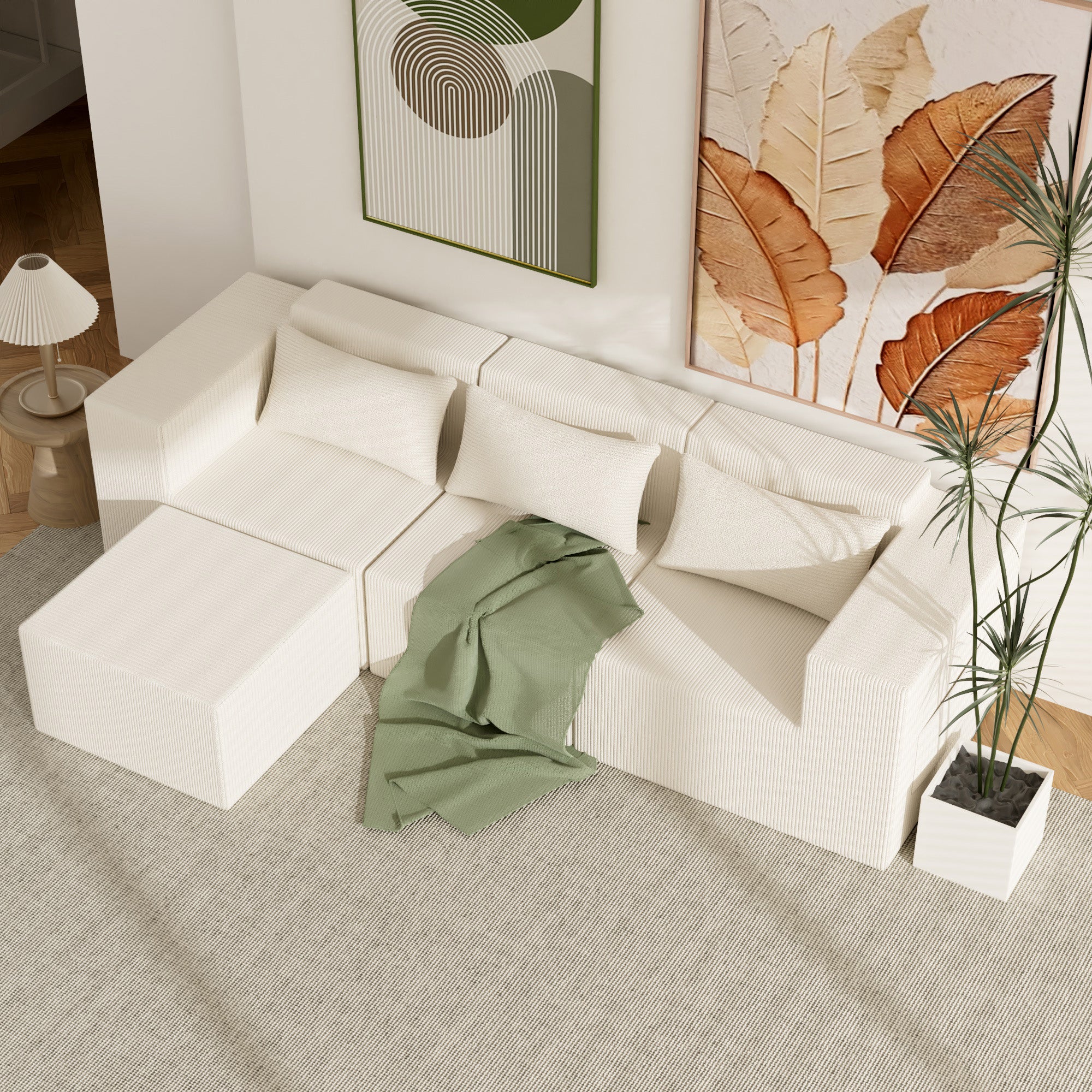 White sectional sofa with a green blanket in a living room setting.