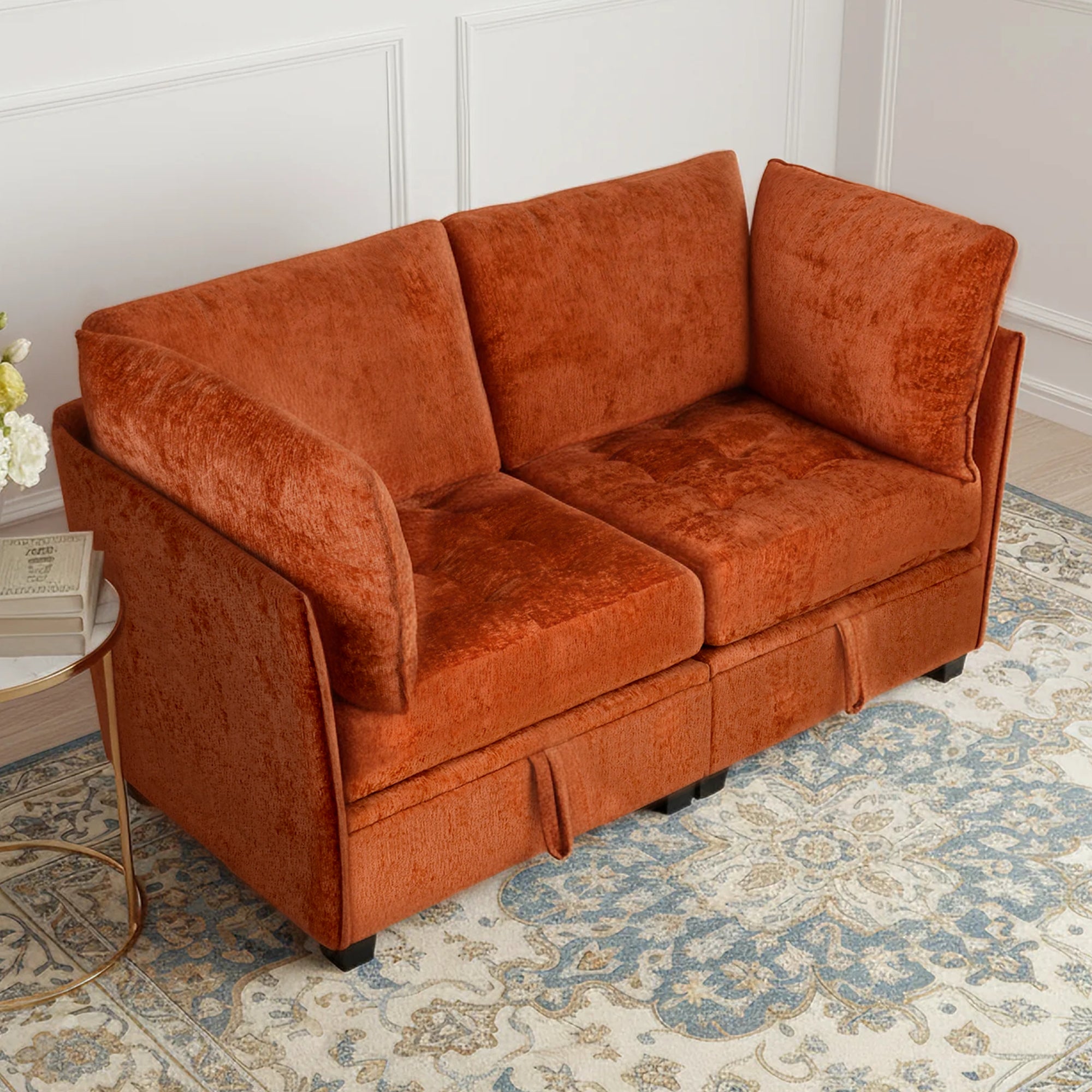 Orange sofa in a room with a patterned rug and side table.