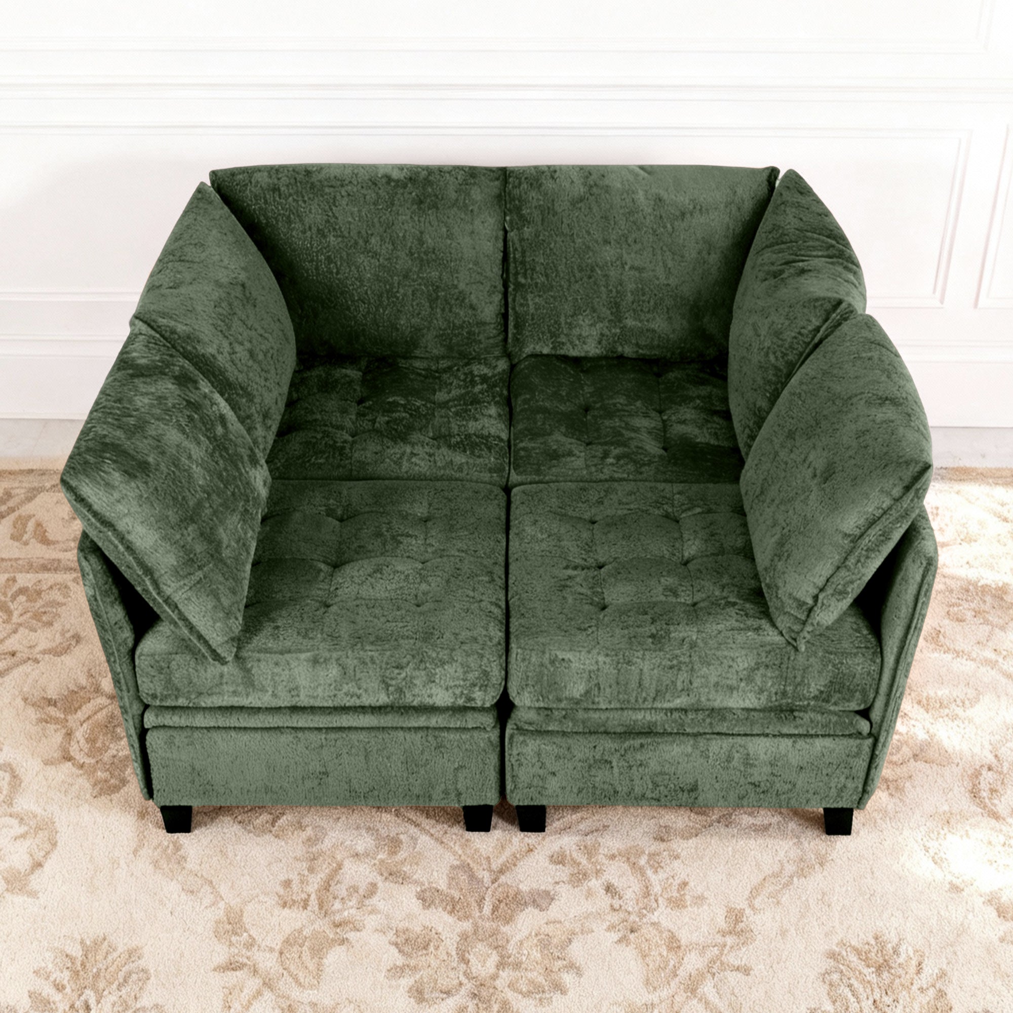 Green sofa on a patterned rug with a white wall background