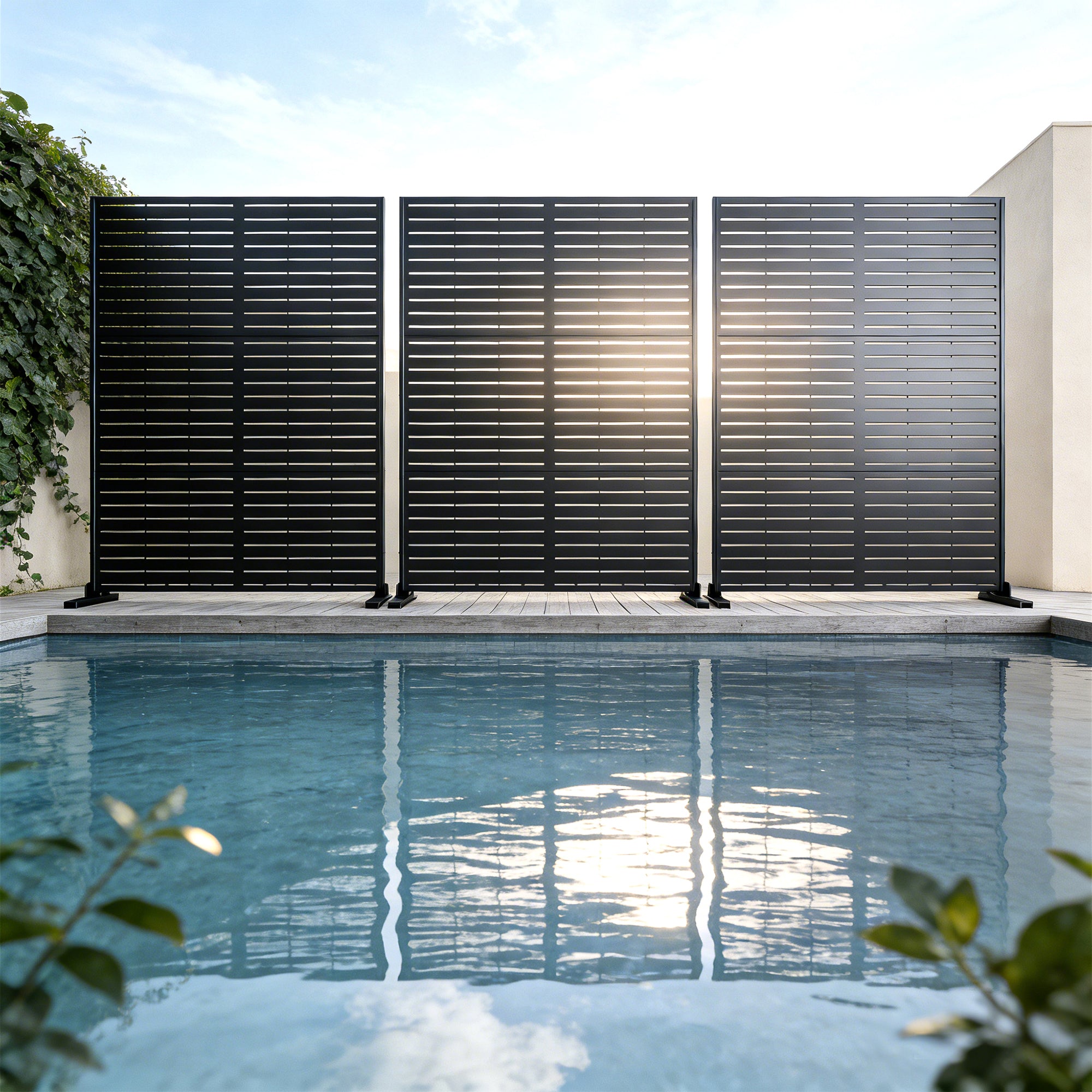 Black poolside privacy screen with a pool and garden in the background
