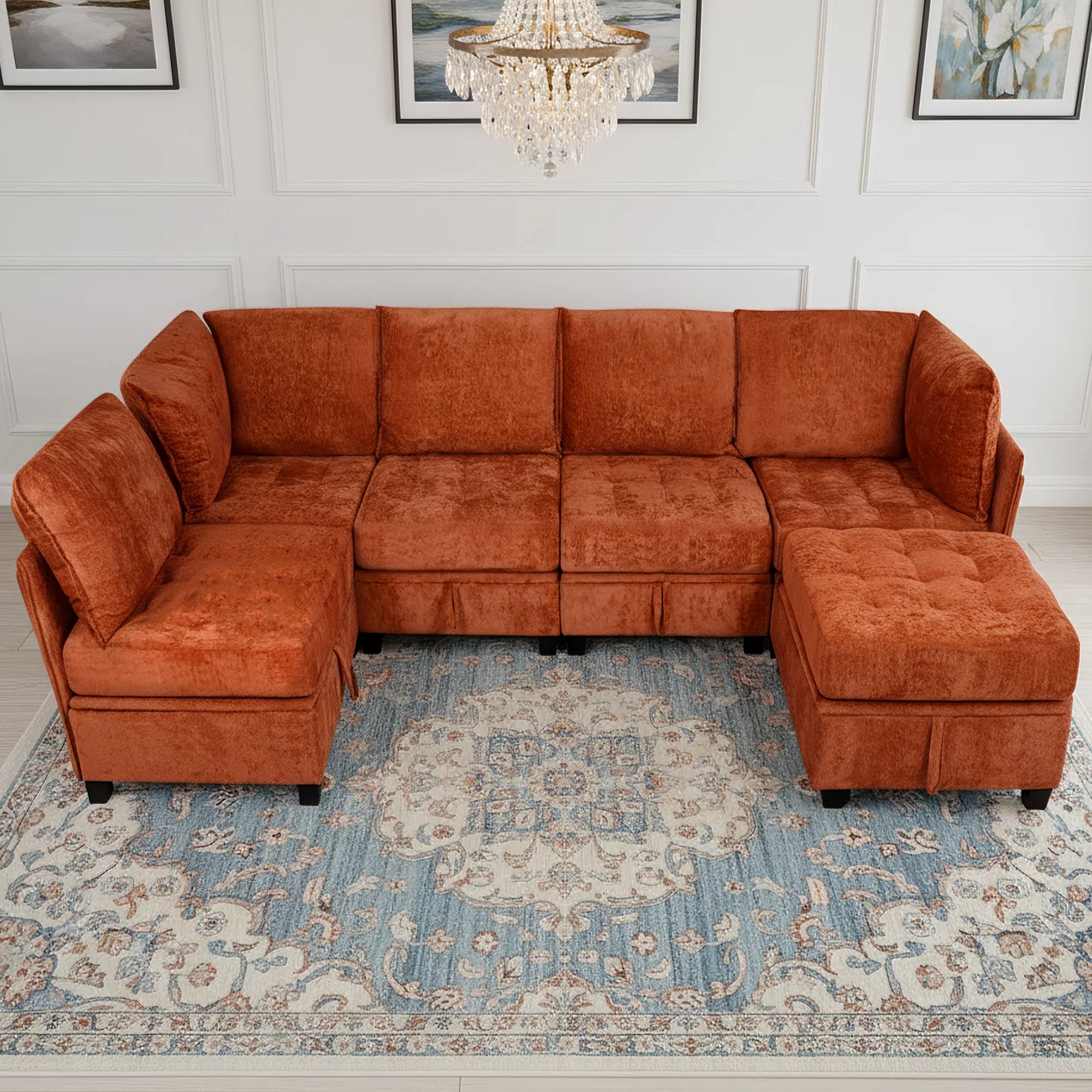 Orange sectional sofa in a living room with a chandelier and framed pictures on the wall.