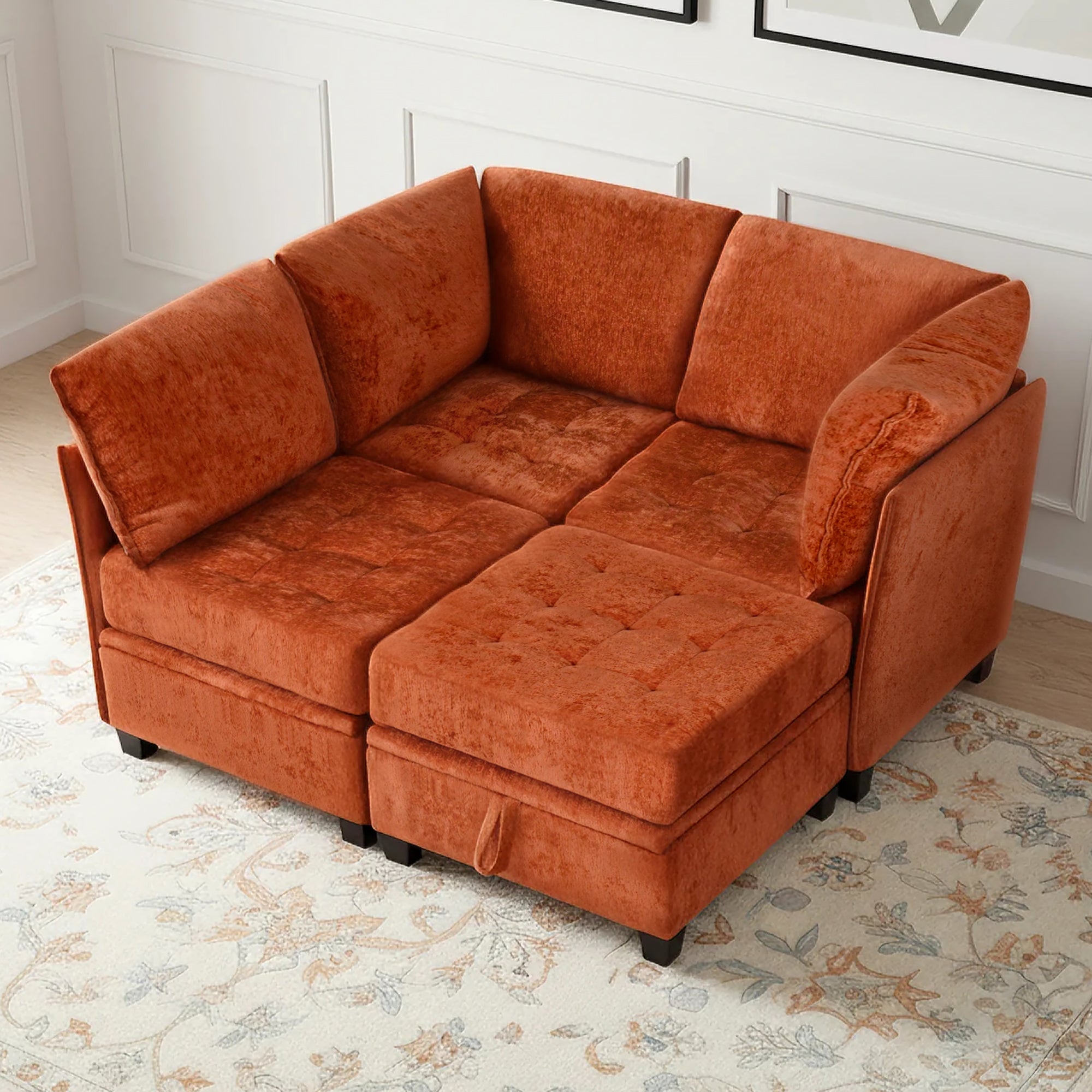 Orange sectional sofa in a room with a floral rug and white walls.