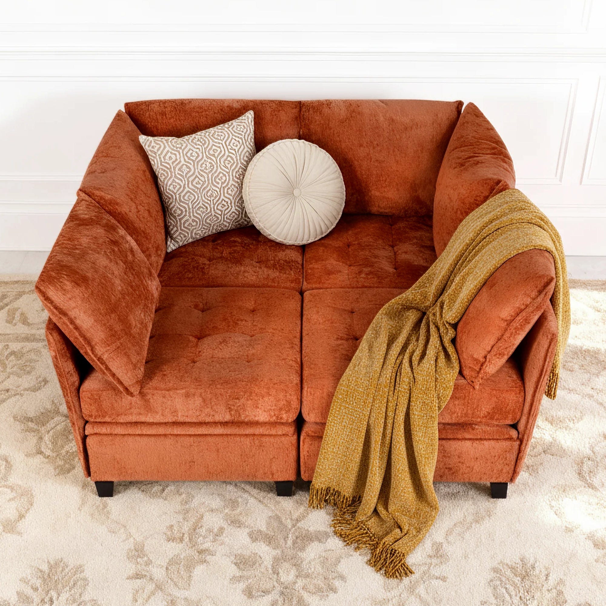 Orange sofa with decorative pillows and a blanket on a patterned rug