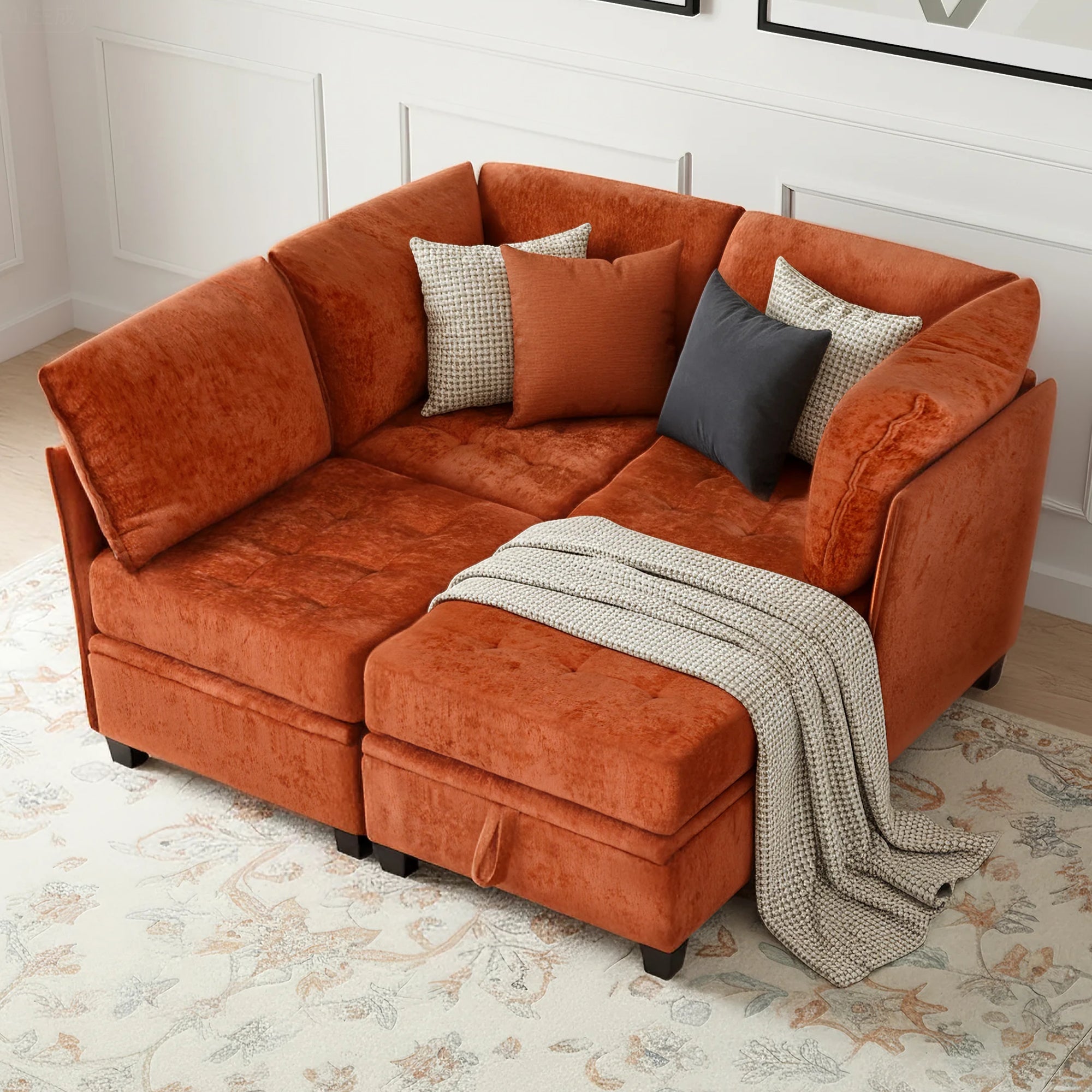 Orange sectional sofa with cushions and a blanket on a floral rug.