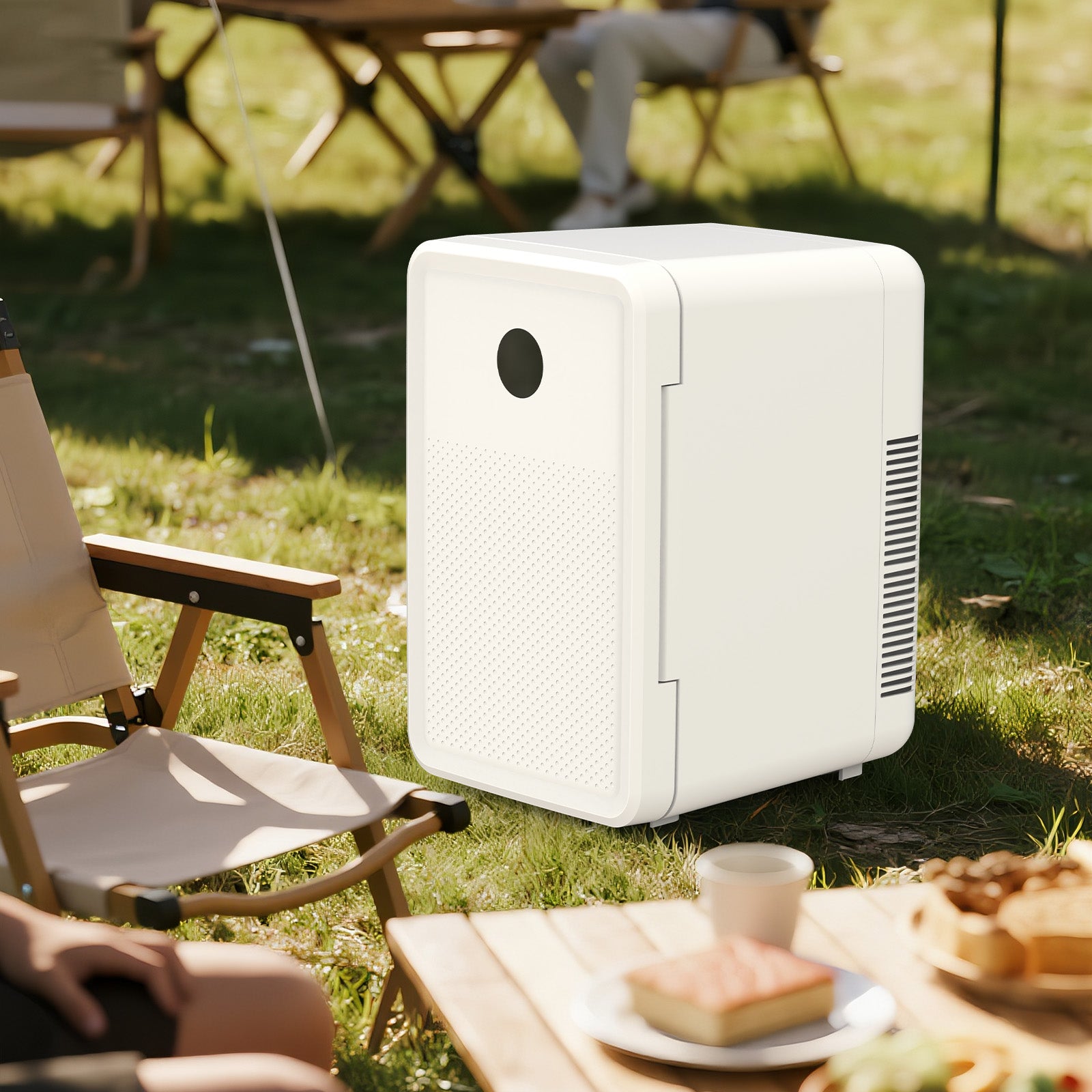 White portable refrigerator on grass with outdoor furniture and food in the background