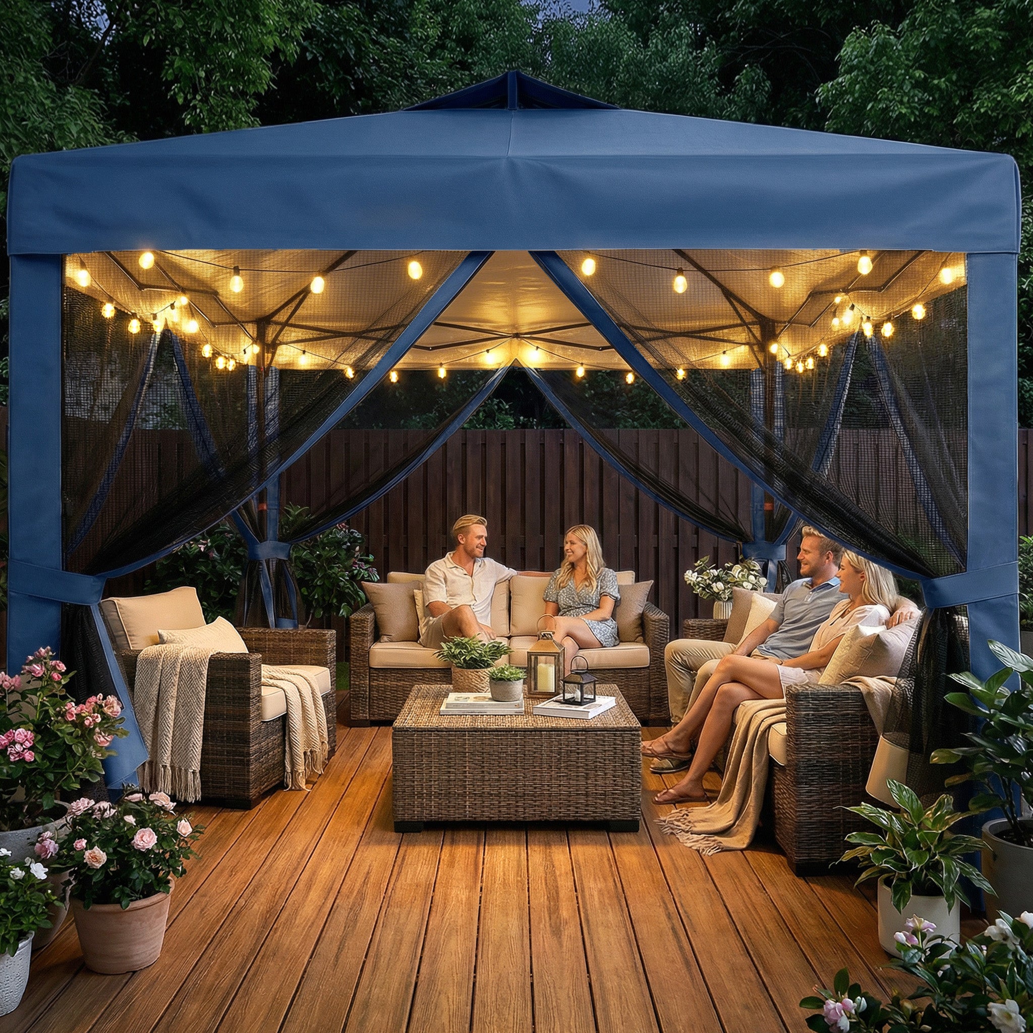 People sitting under a blue outdoor canopy with string lights on a wooden deck.