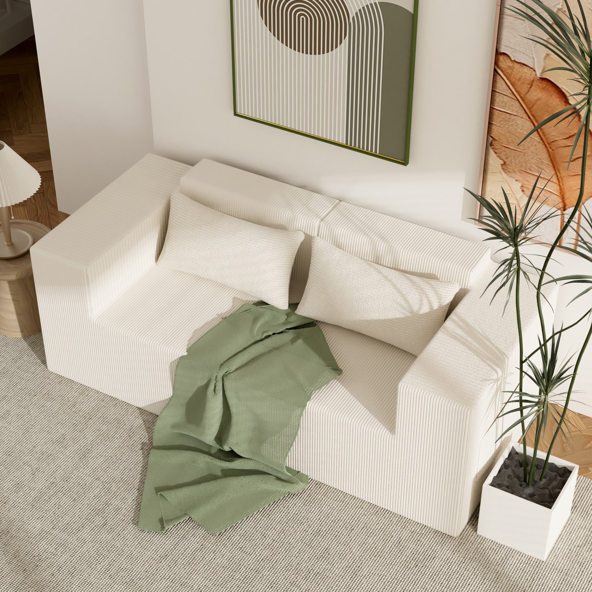 Beige sectional sofa with a green blanket in a living room setting.