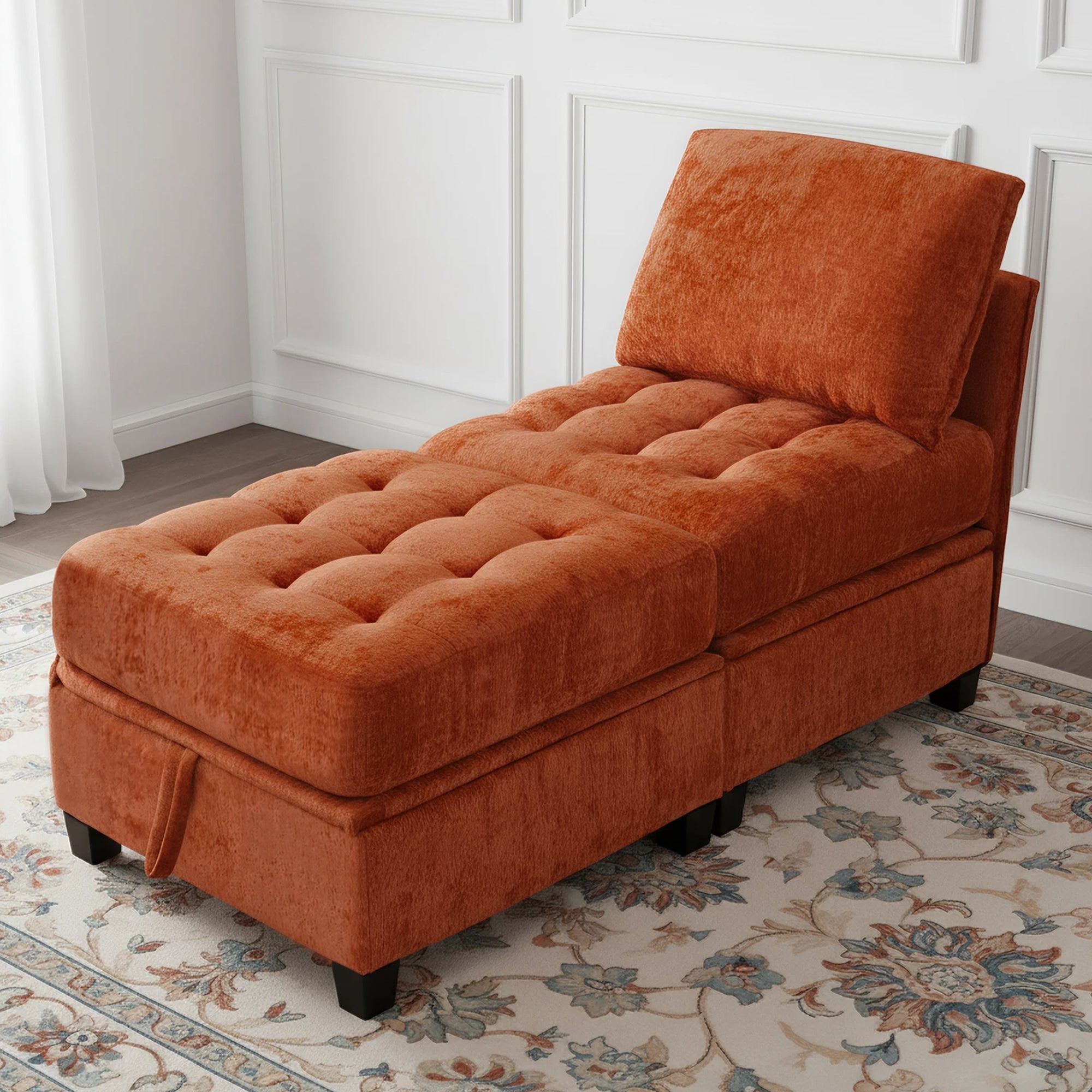 Orange tufted chaise lounge in a room with white walls and a patterned rug.