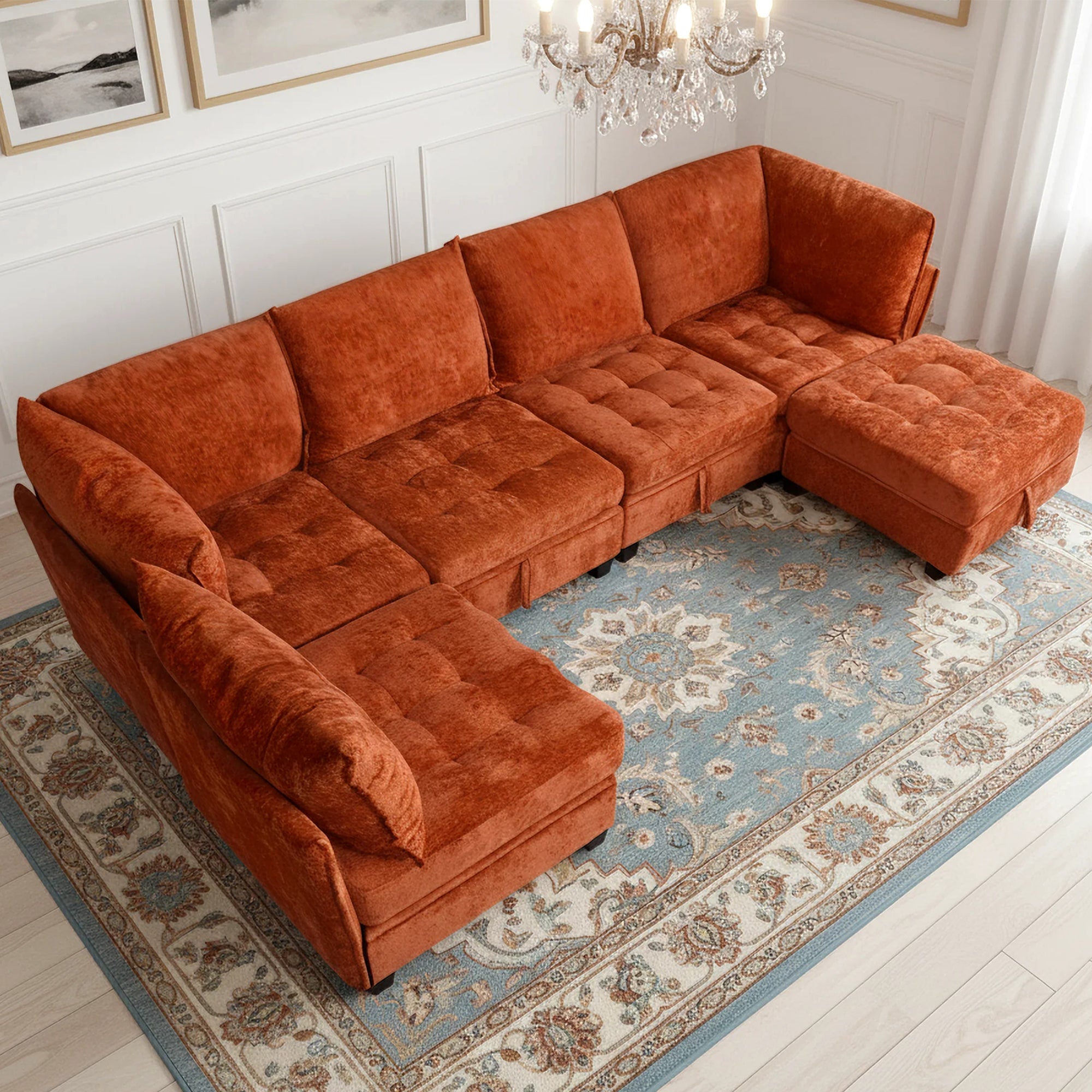 Orange sectional sofa in a living room with a chandelier and framed pictures.