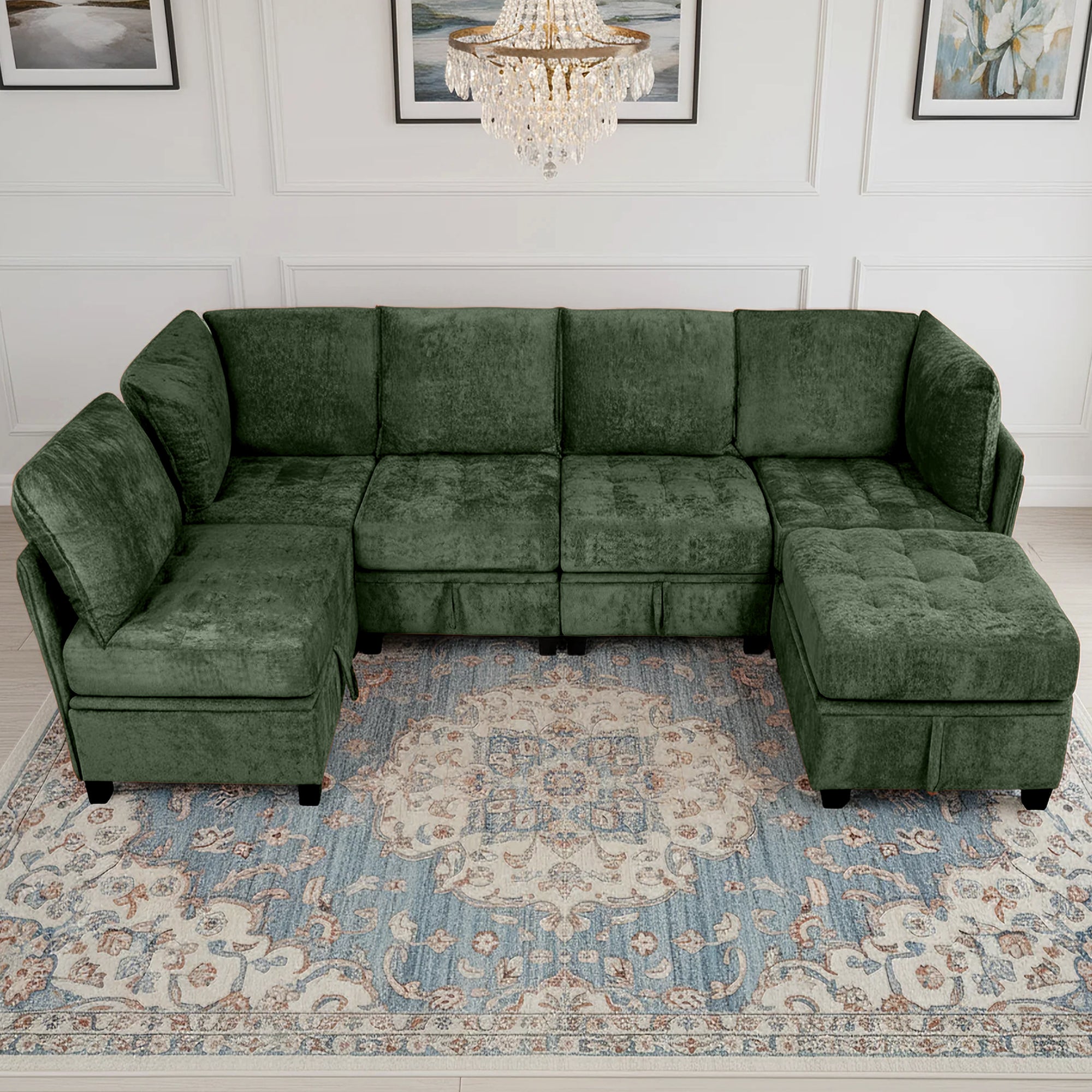 Green sectional sofa in a living room with a chandelier and framed pictures on the wall.