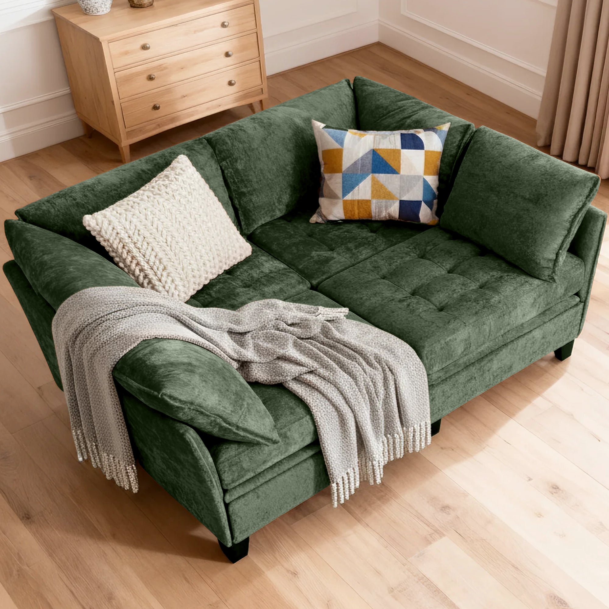 Green sofa with cushions and a blanket on a wooden floor