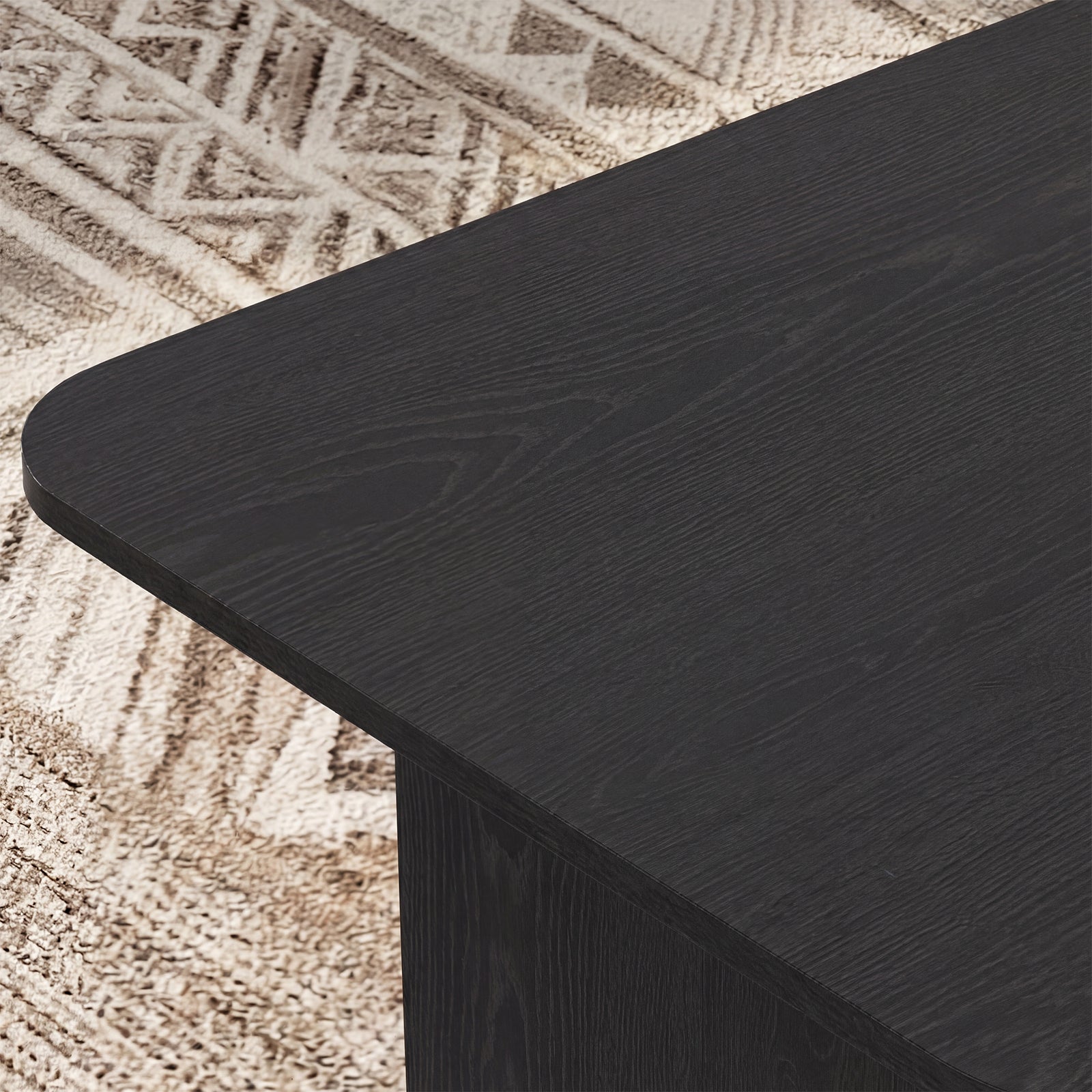 Close-up of a black wooden table corner on a textured beige surface